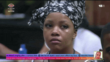 a woman wearing a head scarf is sitting in front of a big brother screen