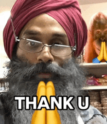 a man with a beard wearing glasses and a red turban says " thank u "