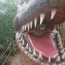 a dog is sticking its head out of a dinosaur statue .