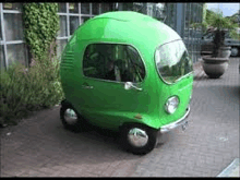 a green car is parked on a brick sidewalk .