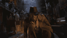 a man in a cowboy hat and trench coat is walking through a dark room