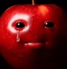 a red apple with a crying eye and a tear coming out of it .