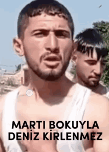 a man with a beard is standing in front of a sign that says marti bokuyla