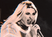 a woman is singing into a microphone with her mouth wide open