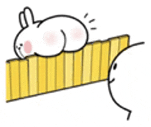 a rabbit is laying on top of a yellow fence next to a person .