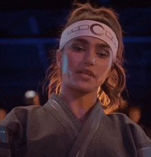 a woman in a karate uniform is wearing a headband .