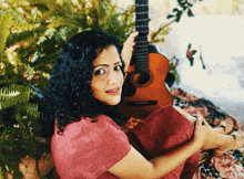 a woman in a red dress holds a guitar