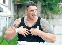 a man with a lot of tattoos on his arms and chest is wearing a watch