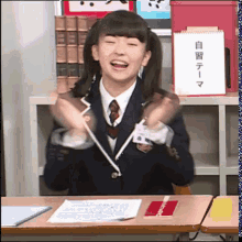 a girl in a school uniform is sitting at a desk in front of a sign with chinese writing on it