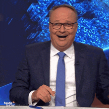 a man in a suit and tie is smiling in front of a blue background with the word heute show on it