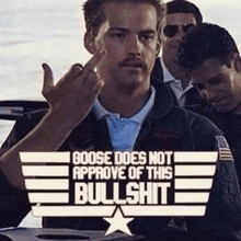 a man with a mustache is giving the middle finger in front of a group of people .