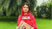 a woman in a red scarf is holding a pillow in a garden .