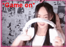 a woman is holding a remote control in front of her face and the words game on are above her