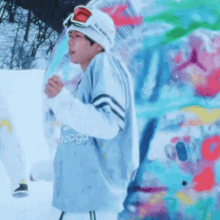 a man wearing a beanie and goggles is standing in the snow .