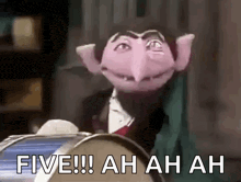 sesame street count von count is giving a five while sitting at a table .