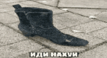 a black boot is sitting on a brick sidewalk with russian writing on it .