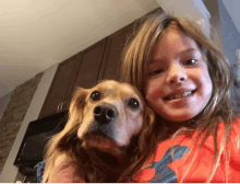 a young girl holds a dog in her arms and smiles