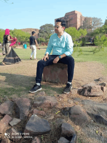 a man sitting on a rock with a redmi 9 prime camera