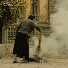 a woman is sweeping the ground with a broom in front of a sign that says la guarinda film festival