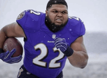 a man wearing a ravens jersey runs with a football