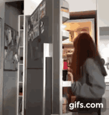 a woman is standing in front of a refrigerator with the door open .