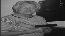 a woman in a striped shirt is holding a gun and pointing