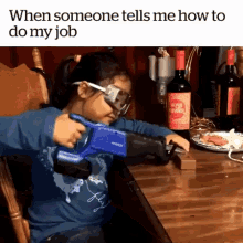 a little girl is sitting in a chair holding a toy gun in front of a bottle of wine .