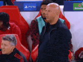 a man sitting in a stadium with a ps5 logo on the wall