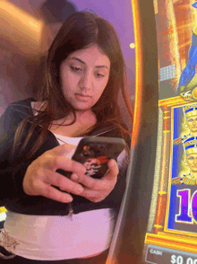 a woman looks at her phone in front of a slot machine that says 10 on it