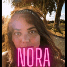 a woman 's face is behind a pink sign that says nora