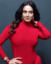 a woman in a red turtleneck holds her hair