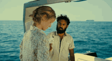 a man and a woman are on a boat in the ocean and the man is holding a camera