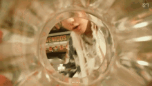 a close up of a person looking through a glass with a sign that says venidos