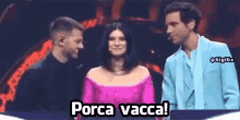 a man in a blue suit stands next to a woman in a pink dress and says porca vacca ..