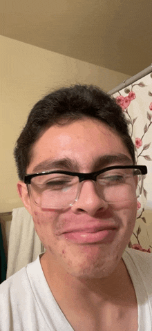 a young man wearing glasses and a white shirt makes a funny face