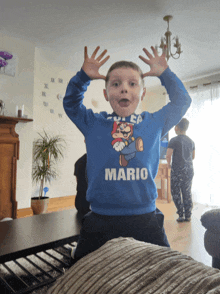 a young boy wearing a blue mario sweater is making a funny face