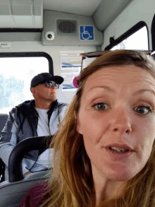 a man and a woman are sitting on a bus with a handicap sticker on the ceiling above them