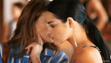 a couple of women are kissing each other and one of them is touching the other 's face .