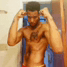 a shirtless man is flexing his muscles in front of a mirror in a locker room .