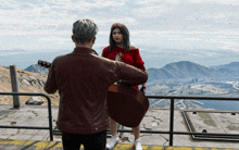 a man is playing a guitar to a woman on a balcony