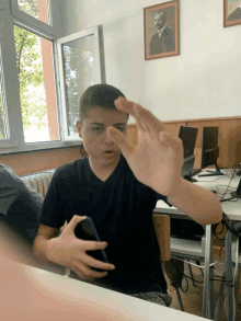 a boy sitting at a desk with a picture of a man on the wall