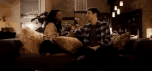 a man and a woman are sitting on a couch and holding hands .