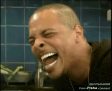 a man is laughing with his eyes closed and his tongue hanging out
