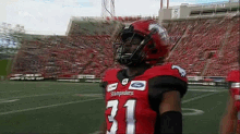 a football player wearing a red and black uniform with the number 31 on it is standing on a field .