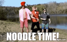 a group of men are standing on a beach with the words `` noodle time '' above them .