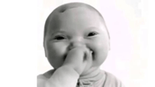a baby covering his mouth with his hand and smiling