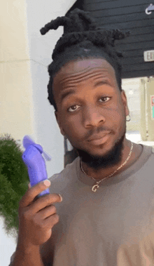 a man with dreadlocks and a beard is holding a purple fan