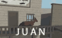 a goat is standing on a railing in front of a building with the name juan written on it .