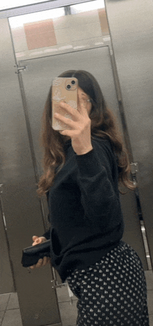 a woman takes a selfie in a public restroom