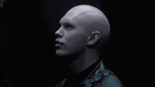 a man with a shaved head is wearing a black jacket